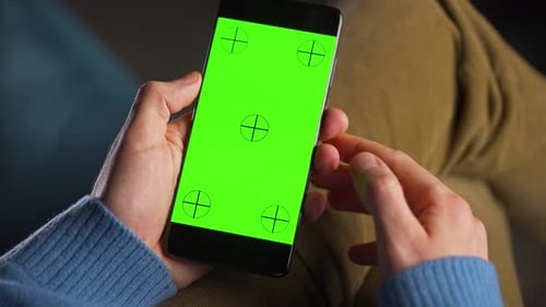 Man Using Smartphone with Green Mockup Screen in Vertical Mode