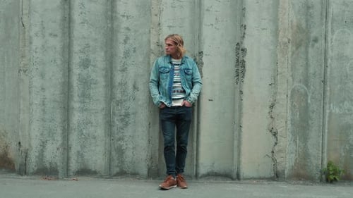 Man Leaning Against Wall in Urban Setting