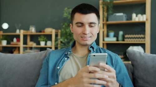 Man Uses Smartphone on Couch at Home