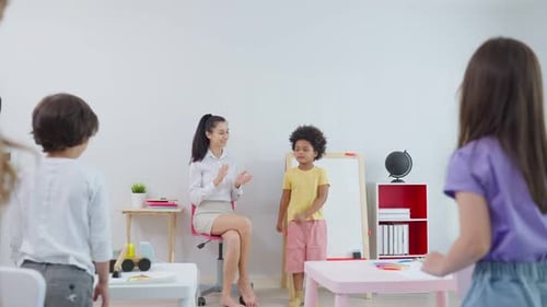 Caucasian beautiful woman teacher teaching a lesson to kid student in classroom at school.
