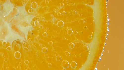 Luftblasen um eine Orangenscheibe.