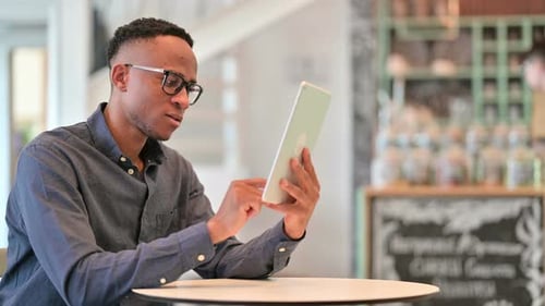 Serious African Man Using Tablet in Cafe