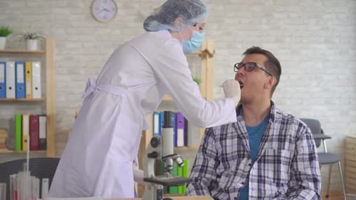 Ärztin macht einen Speicheltest aus dem Mund eines Mannes mit einem Wattestäbchen Nahaufnahme