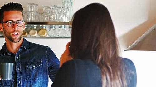 Man Talking to Woman in Kitchen with Mug