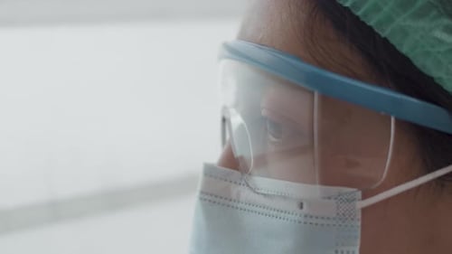 Close-up doctor or nurse exhausted and looking outside a window while resting working.