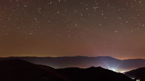 Starry Night Sky Over Mountains With Distant City