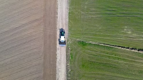 Blue tractor working on field, aerial view in spring