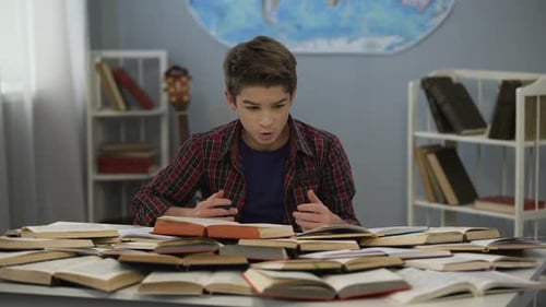 Schoolboy Absently Looking at Huge Pile of Open Books on Table, Doing Homework