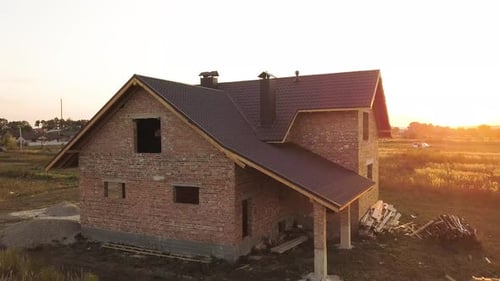 Aerial view of unfinished house with wooden roof structure covered with metal tile sheets under