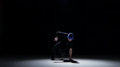 Tänzerin Man in Hat beginnt Breakdance auf Schwarz zu tanzen