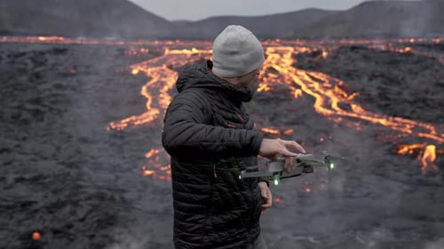 Man operating drone near flowing lava field