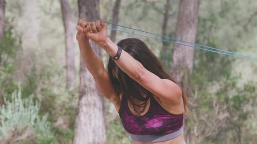 Side view of sportswoman exercising with elastic band in park