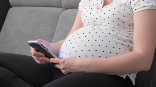 Pregnant Woman Relaxing at Home with Phone