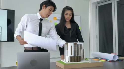 Business man and woman working with paper and building model