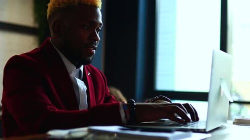 Smiling Businessman Working on Laptop Computer in Office