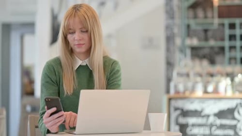 Young Woman Working on Smartphone and Laptop in Cafe in Cafe