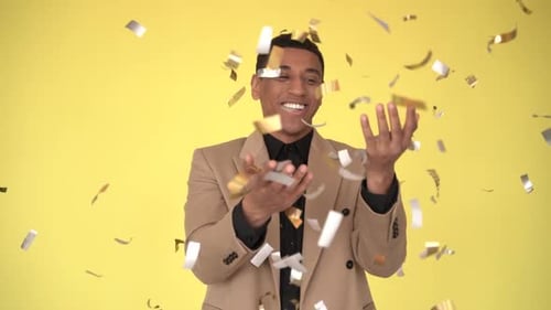 Man Throws Confetti in Celebration on Yellow Background