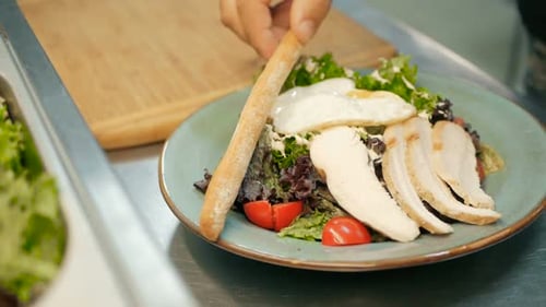 chef puts the grisini on a salad in a restaurant kitchen. cooking salad step by step
