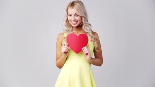 Young Woman Holding Out a Red Heart