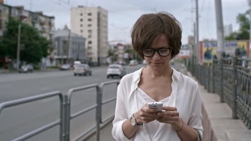 Woman Walking along Street with Smartphone