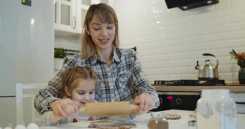 Woman and Child Rolling Dough in Kitchen