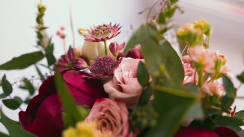 Bouquet with Aromatic Flowers and Green Leaves on Table