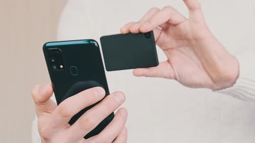 Joven usa un teléfono inteligente para escanear el código QR en la billetera de criptomonedas fría para la transacción