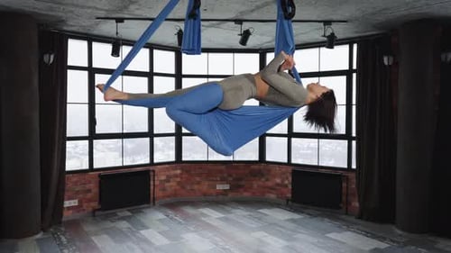 Woman Practicing Aerial Yoga in Bright Room