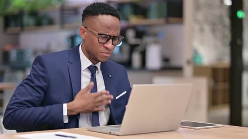 Sick African Businessman with Laptop Coughing in Office
