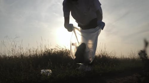 Young Adult Collecting Trash in a Rural Field
