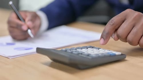 Primer plano de un empresario africano usando una calculadora en el trabajo
