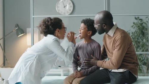 Doctor Examining Boy Patient with Father in Office