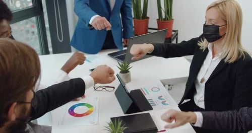 Parceiros de negócios com máscaras faciais batendo os punhos como um sinal de conceito de amizade