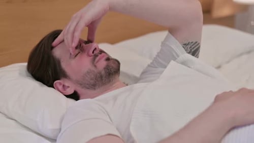 Casual Young Man Having Headache While Sleeping in Bed