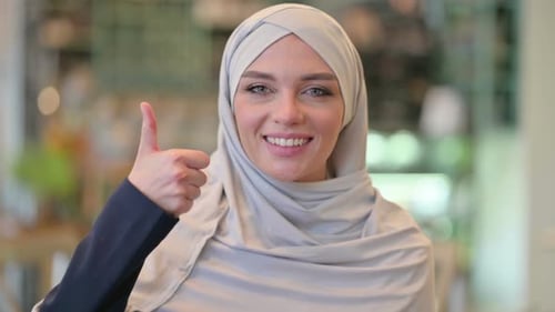 Porträt einer positiven jungen arabischen Frau mit Daumen hoch