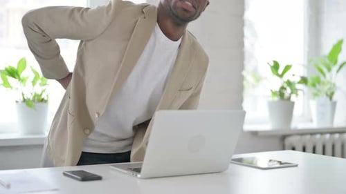 African Man Having Back Pain While Using Laptop in Office