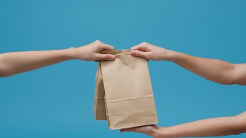 Hands Pass Brown Paper Bag on Blue Background