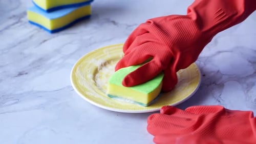 Hands in Gloves Washing Dishes on Marble Counter