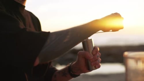 Nahaufnahme lächelnder kaukasischer glücklicher Mann, der Kaffeebohnen mit den Händen in manueller Kaffeemühle im Freien mahlt