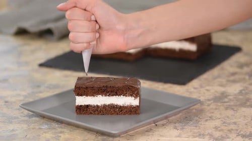 Piping White Frosting on Chocolate Cake Piece