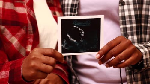 Hopeful Couple Holding Ultrasound of Baby