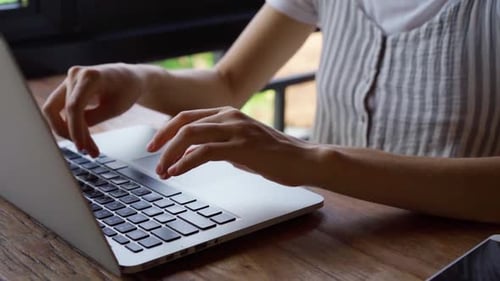 Close up of woman's hands typing on laptop.