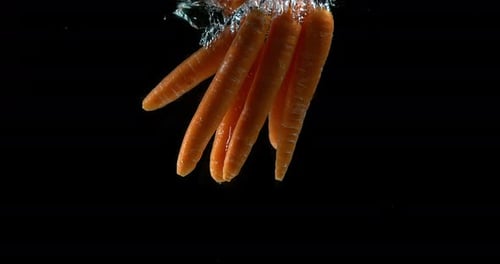 Bright Orange Carrots Dropping Into Clear Water