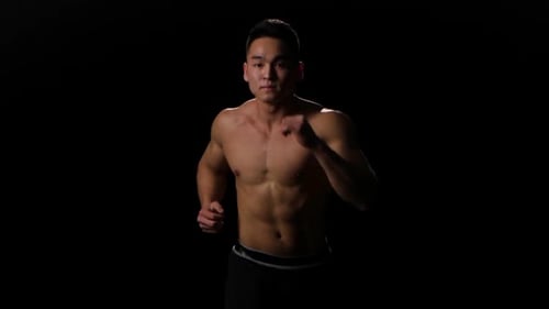 Muscular Man Running in Place Against Black Background