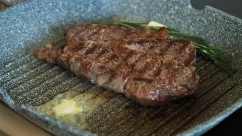 Steak Sizzling in Pan with Butter and Rosemary
