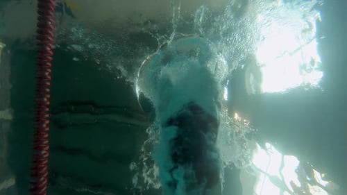 Reflection on the Water in an Indoor Swimming Pool As a Person Dives in Causing Turbulence and Air