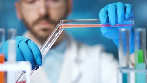Gros plan des mains d'un chimiste professionnel versant un liquide réactif à l'aide d'un bécher en laboratoire