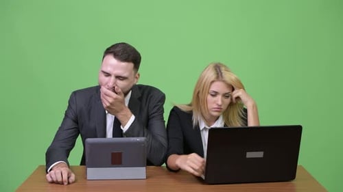 Joven pareja de negocios que parece aburrida mientras trabajan juntos