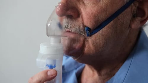 Gros plan d'un homme âgé utilisant un nébuliseur