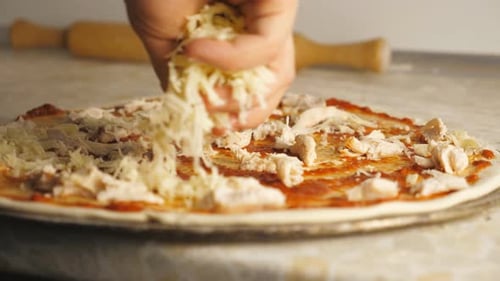 Preparing Pizza By Adding Shredded Cheese